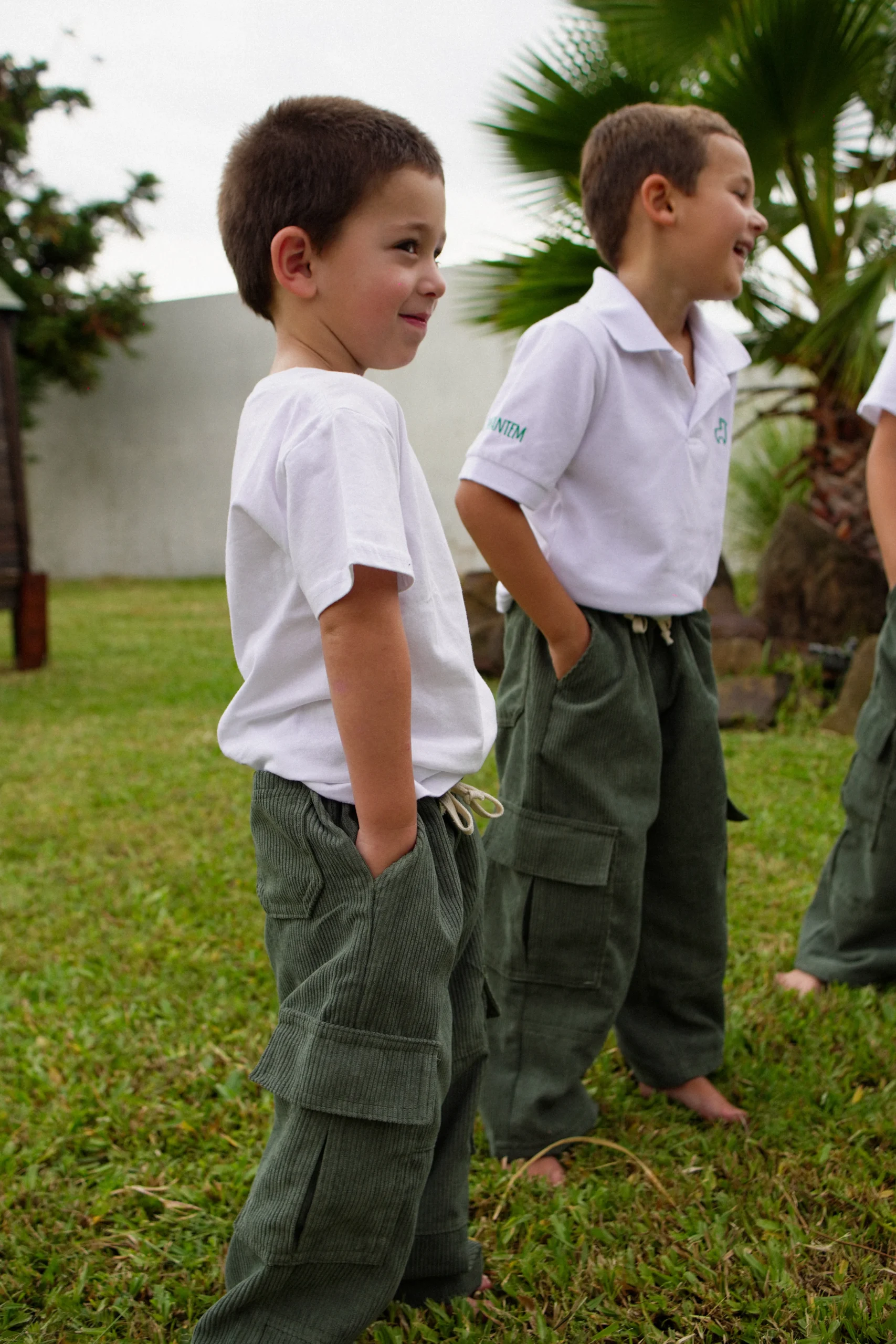 Dos niños sonrientes con camisas polo blancas y pantalones cargo verdes Infantem